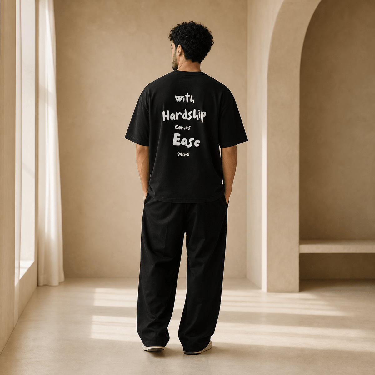 Man wearing the Hardship Comes Ease Black T-shirt, back view - Ummah Collective